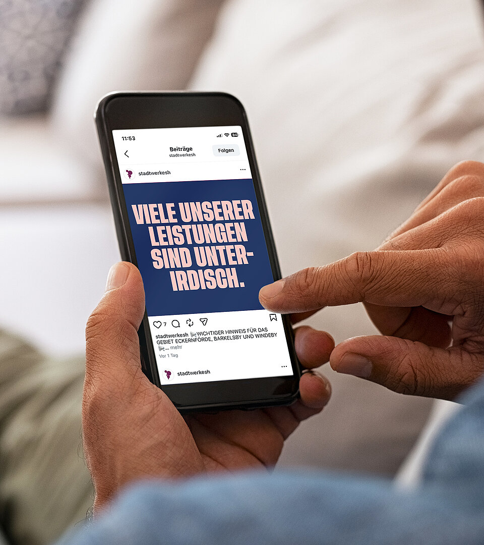 Person liegt auf einem Sofa und hält ein Mobiltelefon mit geöffneter Werbung der Stadtwerke SH in der Hand.