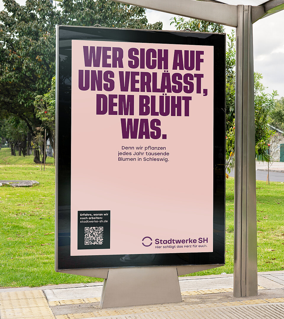 Hier sitzt eine Person in einer Bushaltestelle und scannt mit dem Mobiltelefon den QR-Code eines Stadtwerke SH Werbeplaktes ab.